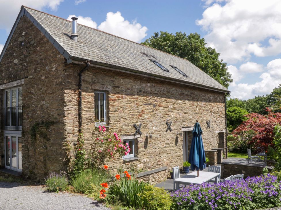 An outdoor area with a building, table, chairs, and plants at The Hay Barn in Halwell