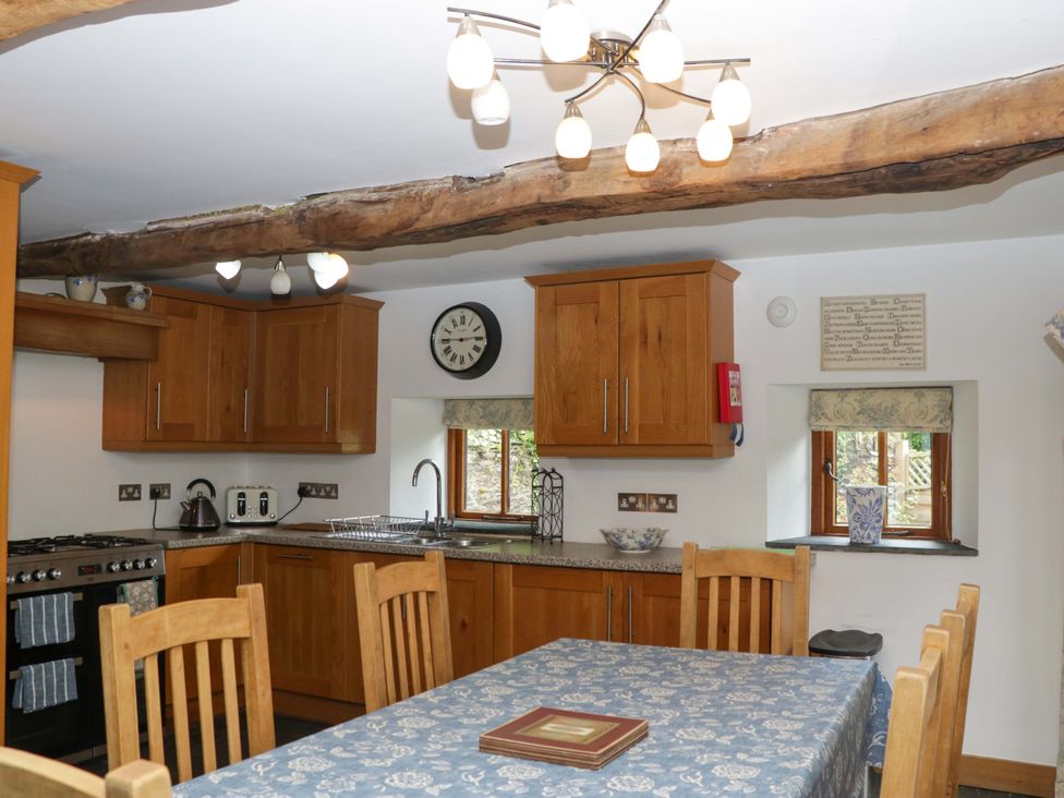 A kitchen with wooden cabinets and a dining table at The Hay Barn in Halwell