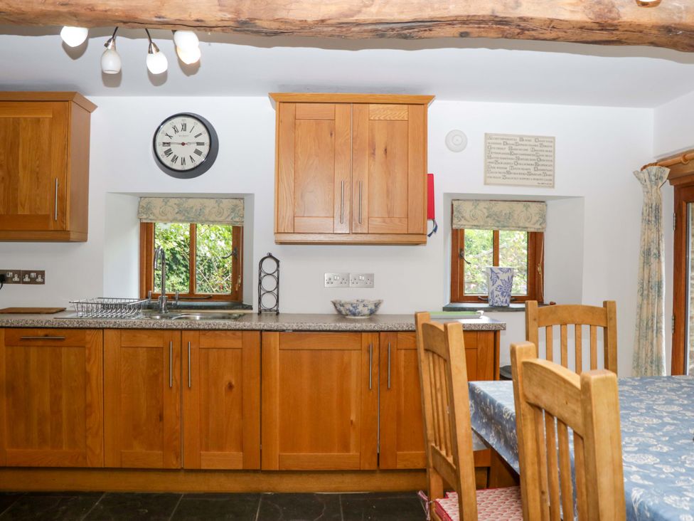 A kitchen with wooden cabinets and a sink at The Hay Barn in Halwell