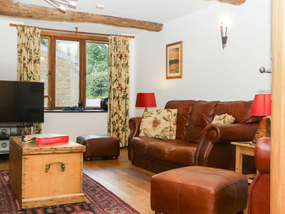 A living room with a sofa and television at The Hay Barn in Halwell