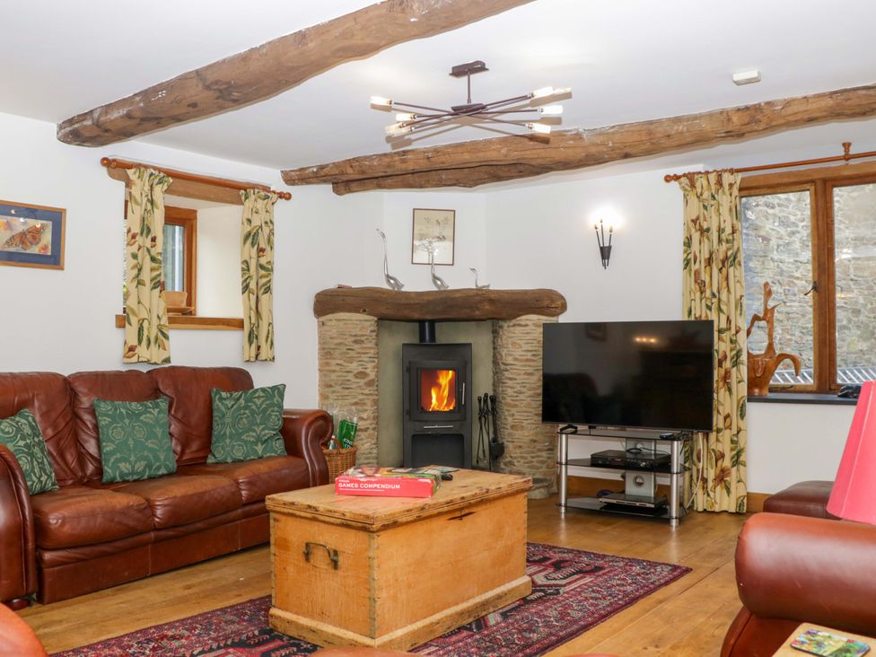 A living room with a fireplace and a television at The Hay Barn in Halwell