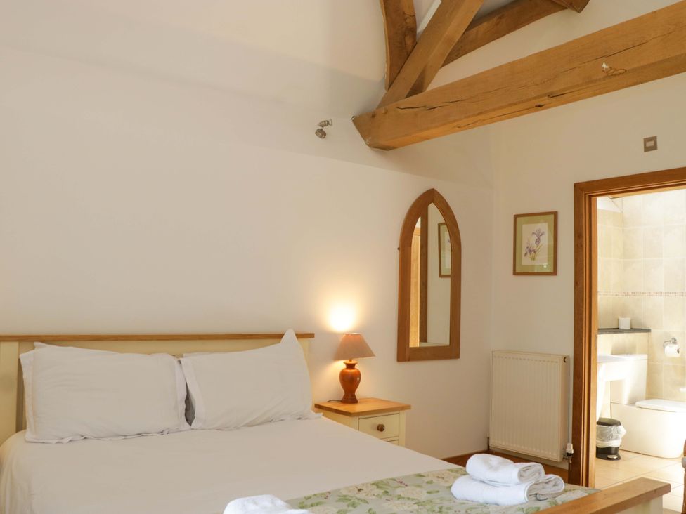 A bedroom with a bed and a bathroom access at The Hay Barn in Halwell
