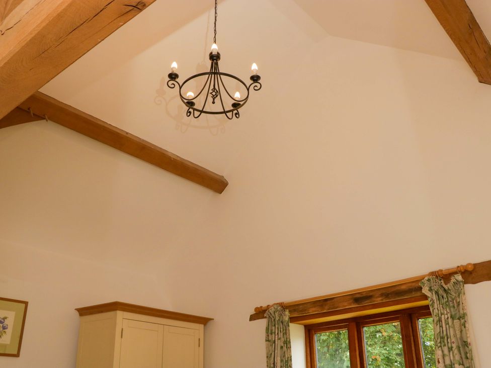 A room with a chandelier and wooden beams at The Hay Barn in Halwell