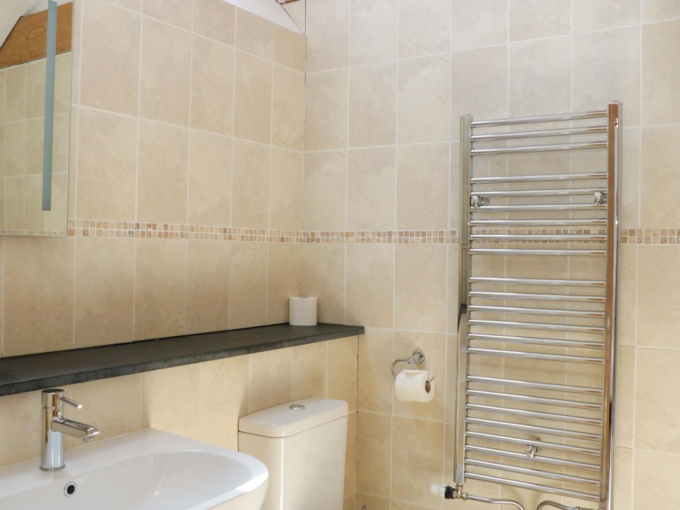 A bathroom with a wash basin, toilet, and towel radiator at The Hay Barn, Halwell