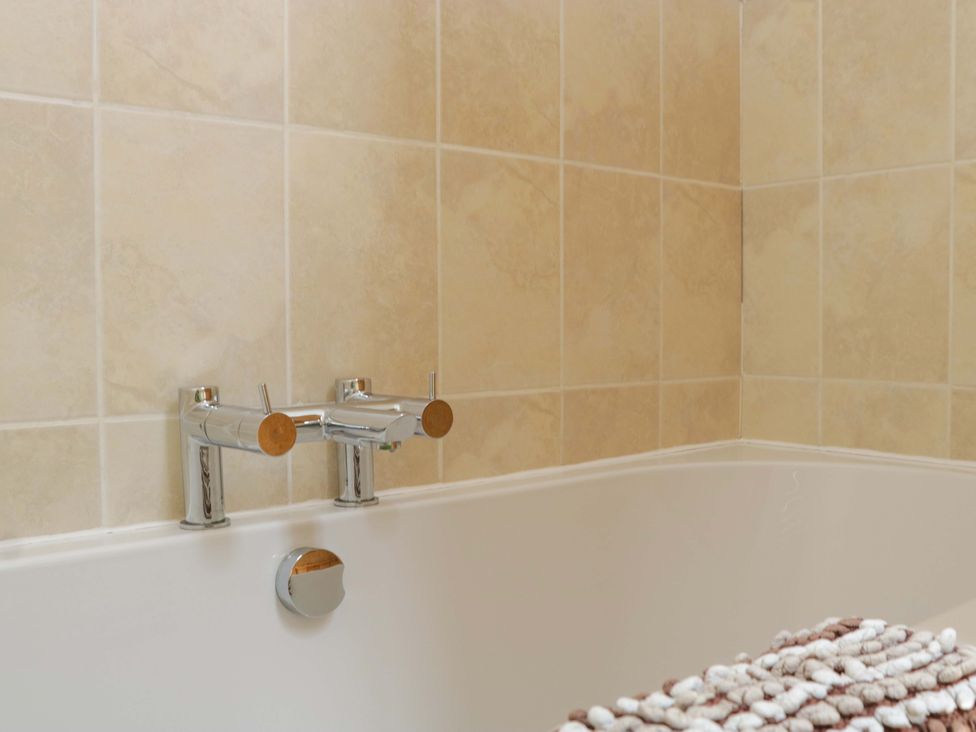 A bathroom with a bathtub and faucet controls at The Hay Barn in Halwell