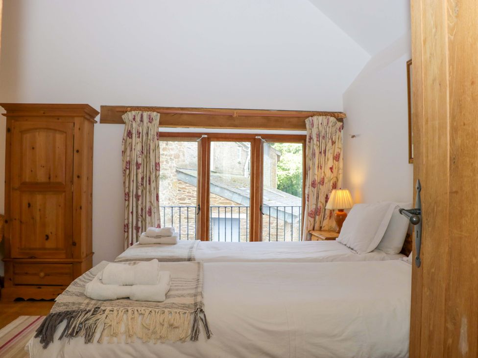 A bedroom with a bed and wardrobe at The Hay Barn in Halwell