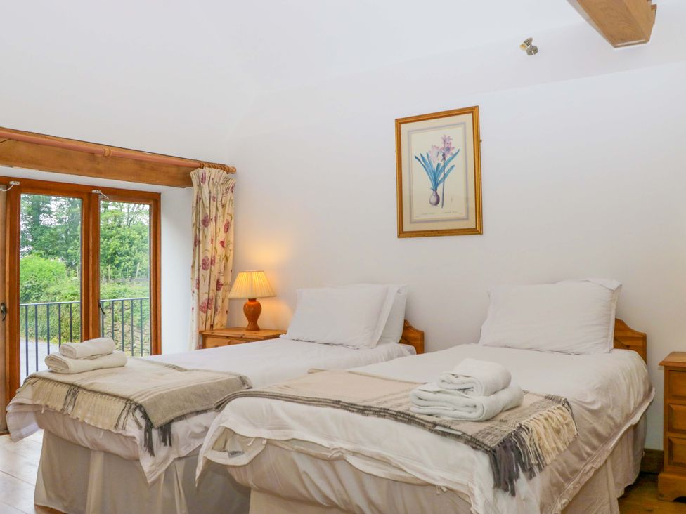 A bedroom with two beds and a window at The Hay Barn in Halwell