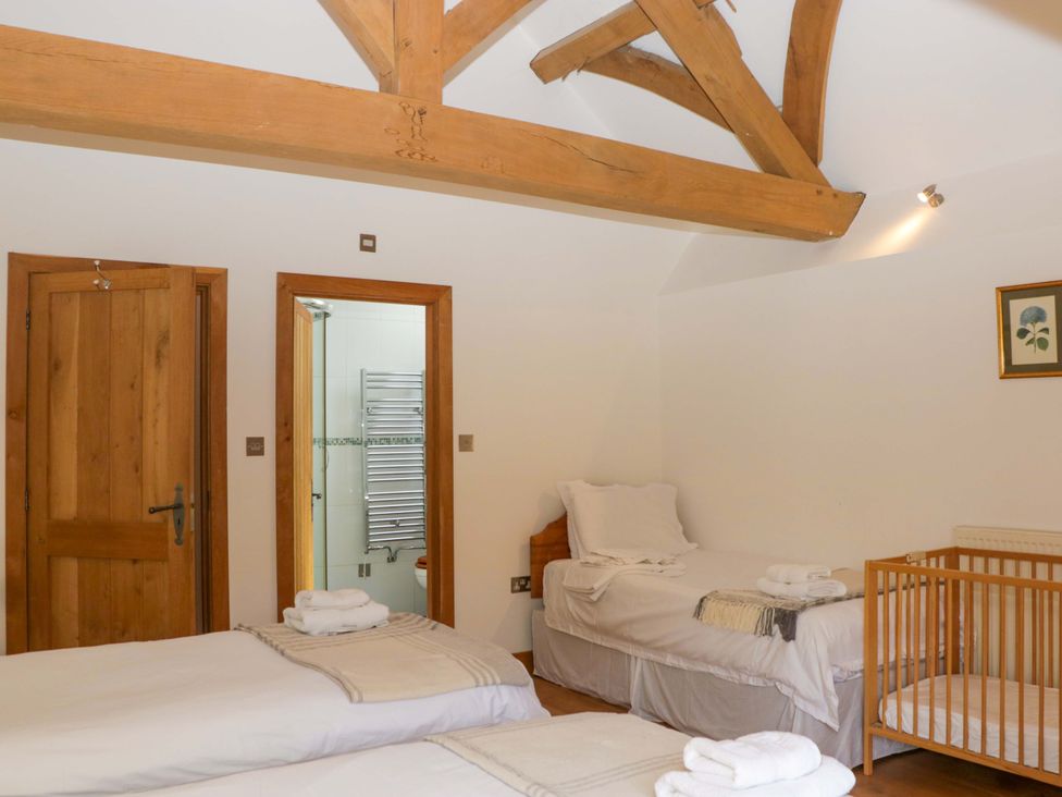 A bedroom with beds and a crib at The Hay Barn in Halwell