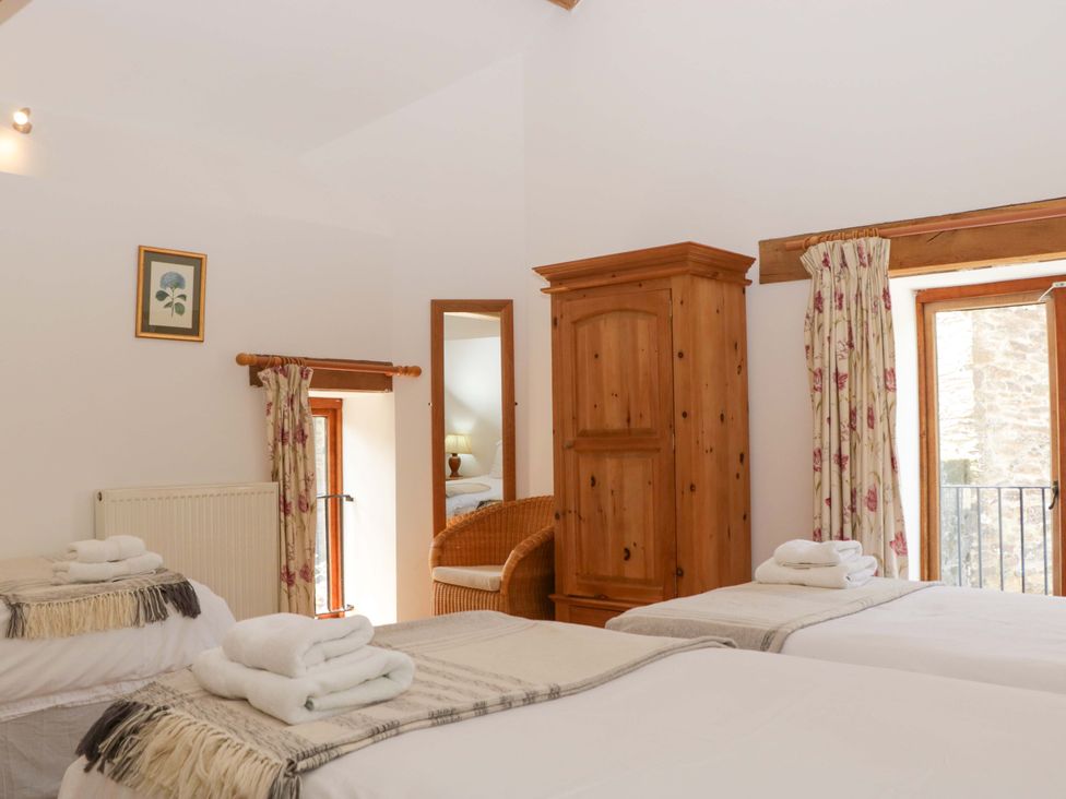 A bedroom with two beds and a wardrobe at The Hay Barn in Halwell