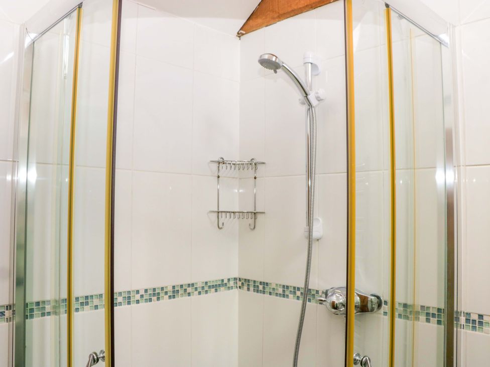 A shower with a glass door and towel rack at The Hay Barn in Halwell