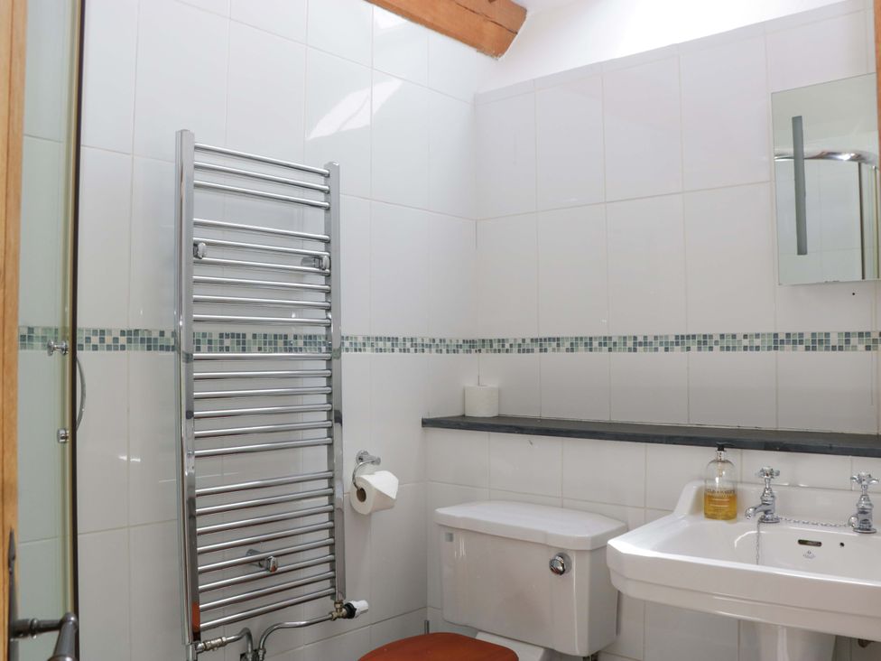 A bathroom with a towel rail, toilet, and sink at The Hay Barn in Halwell