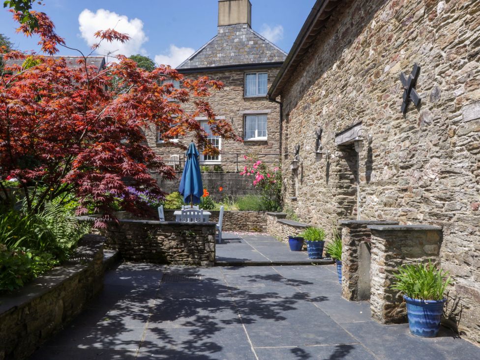 A garden with a stone wall and slate patio at The Hay Barn in Halwell