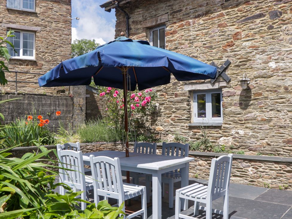 An outdoor dining area with a table and umbrella at The Hay Barn in Halwell