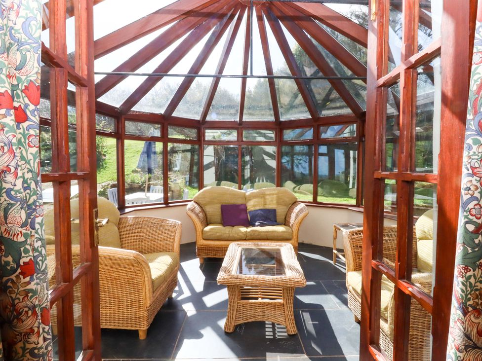 A conservatory with seating and a table at Oak Tree in Halwell