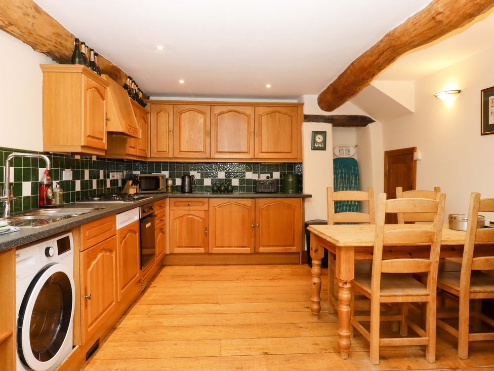 A kitchen with cabinets and a dining table at Oak Tree in Halwell
