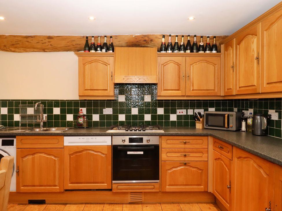 A kitchen with wooden cabinets and appliances at Oak Tree in Halwell