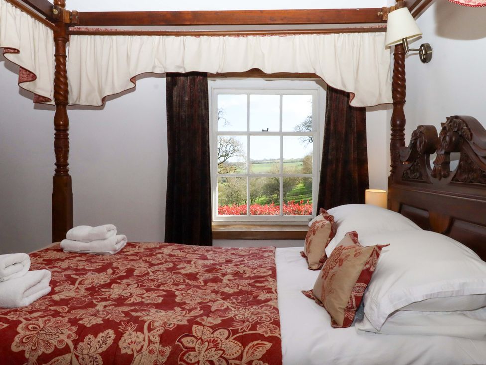 A bedroom with a four-poster bed and a window at Oak Tree in Halwell