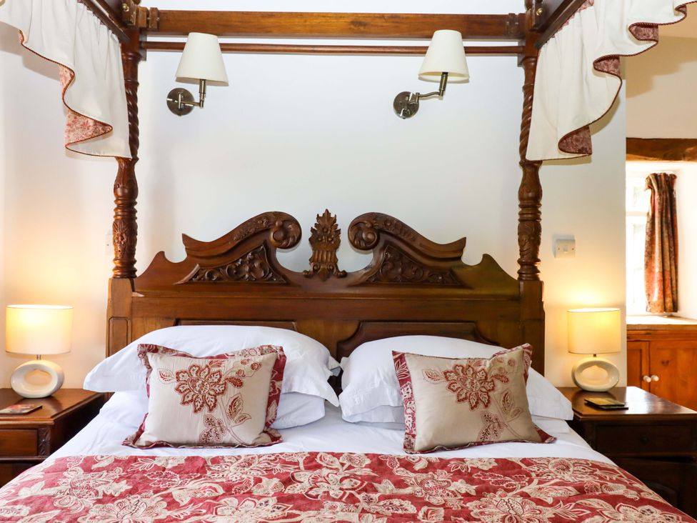 A bedroom with a decorated wooden bed and bedside lamps at Oak Tree in Halwell