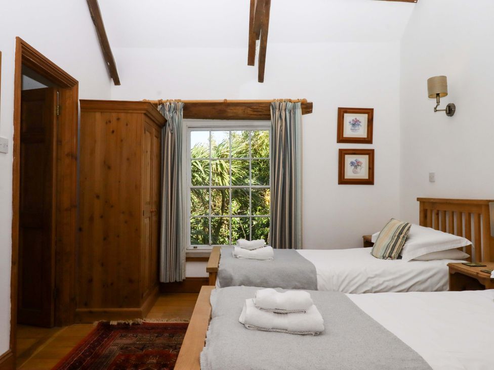 A bedroom with two beds and a wardrobe at Oak Tree in Halwell