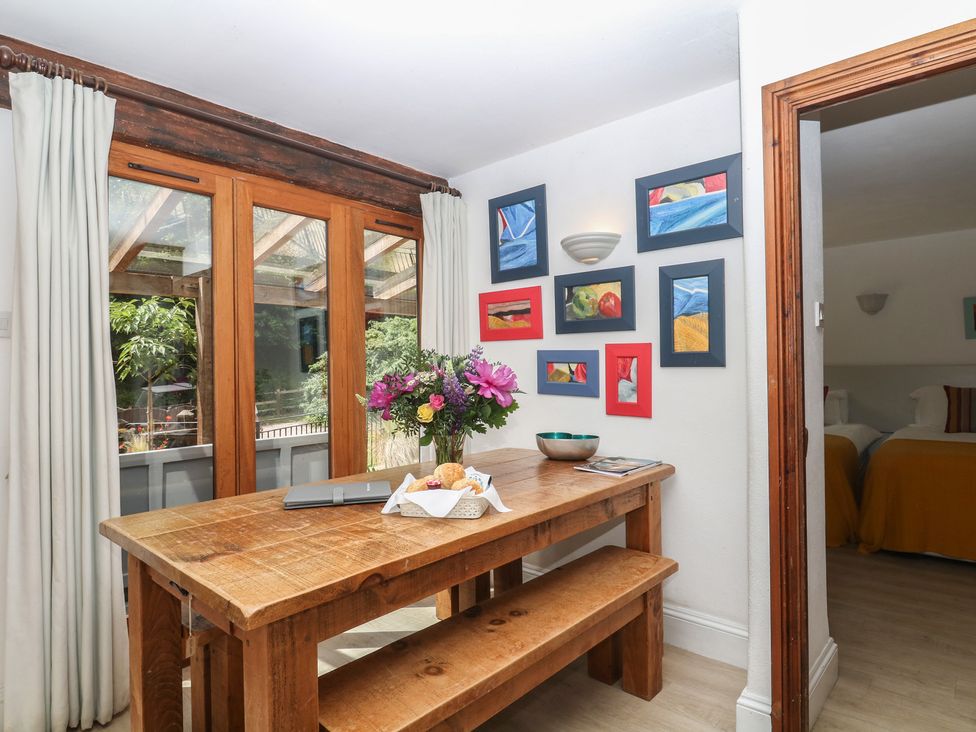A dining room with a wooden table and flower vase at Fixit Cottage in Kingsbridge