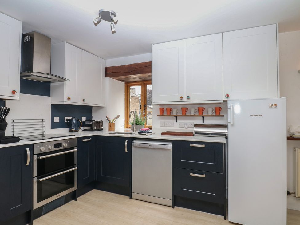 A kitchen with cabinets, sink, oven, and refrigerator at Fixit Cottage in Kingsbridge
