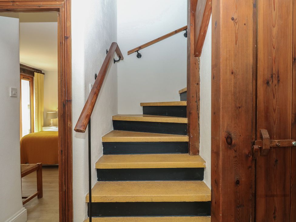 A staircase with handrail leading to an upper floor at Fixit Cottage in Kingsbridge