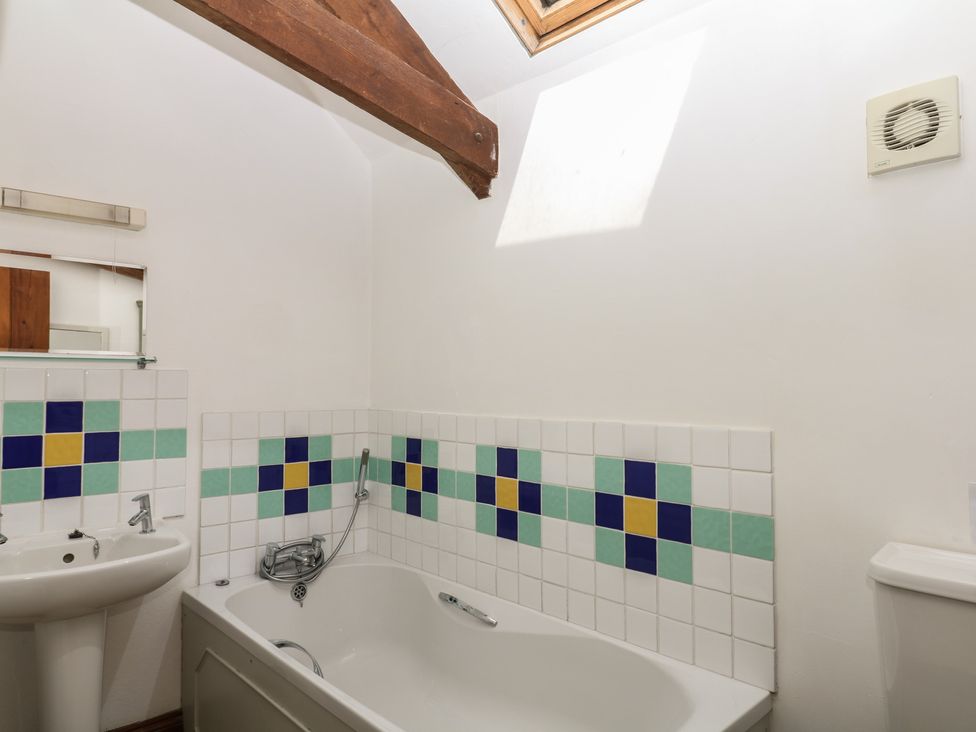 A bathroom with a bath, sink, and toilet at Fixit Cottage in Kingsbridge