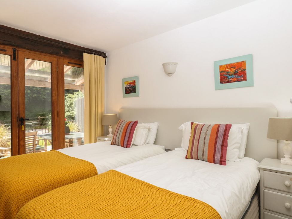 A bedroom with twin beds and sliding doors to a patio at Fixit Cottage in Kingsbridge