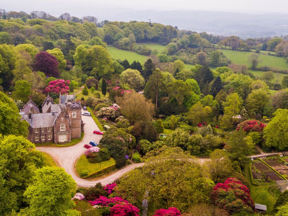 An aerial view of a house surrounded by gardens and trees at The Clock House in Ivybridge