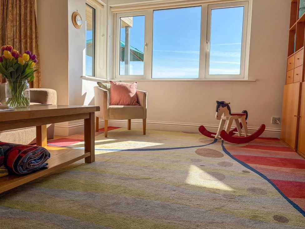 A living room with a vase of tulips and a rocking horse at 5 Burgh Island Causeway Bigbury-on-Sea