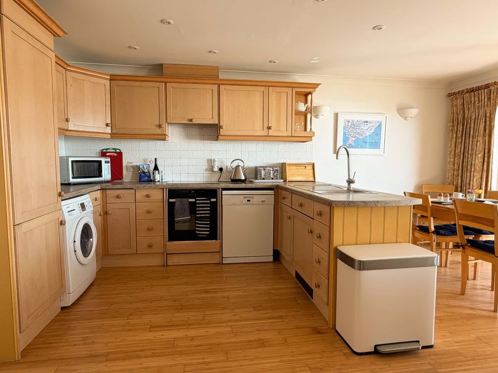 A kitchen with wooden cabinets and appliances at 5 Burgh Island Causeway in Bigbury-on-Sea