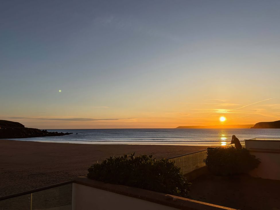 A sunset view over the ocean with a person sitting at 5 Burgh Island Causeway Bigbury-on-Sea