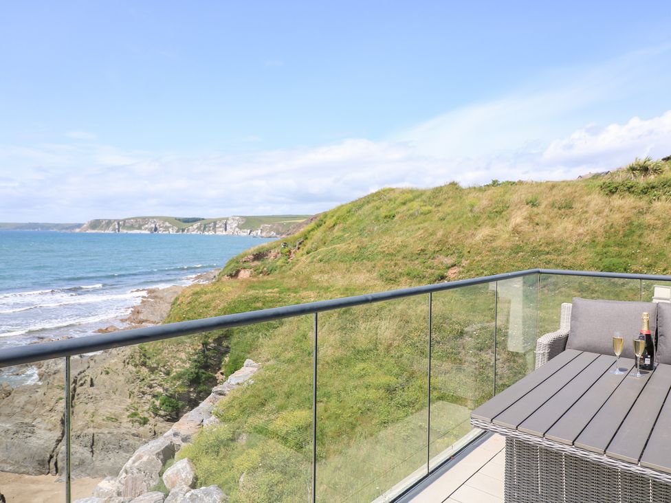 A balcony with a table and chairs overlooking the ocean at 27 Burgh Island Causeway Bigbury-on-Sea