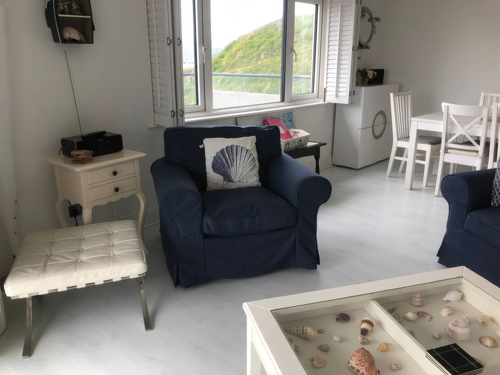 A living room with armchair and table at 27 Burgh Island Causeway Bigbury-on-Sea
