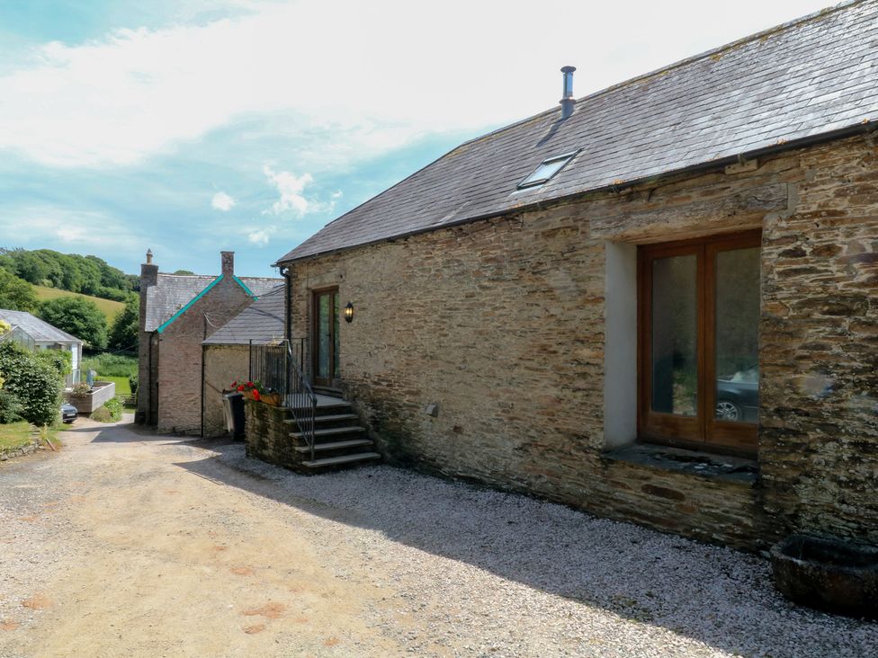 An outdoor area with a stone building and gravel path at Mixit Cottage in Kingsbridge