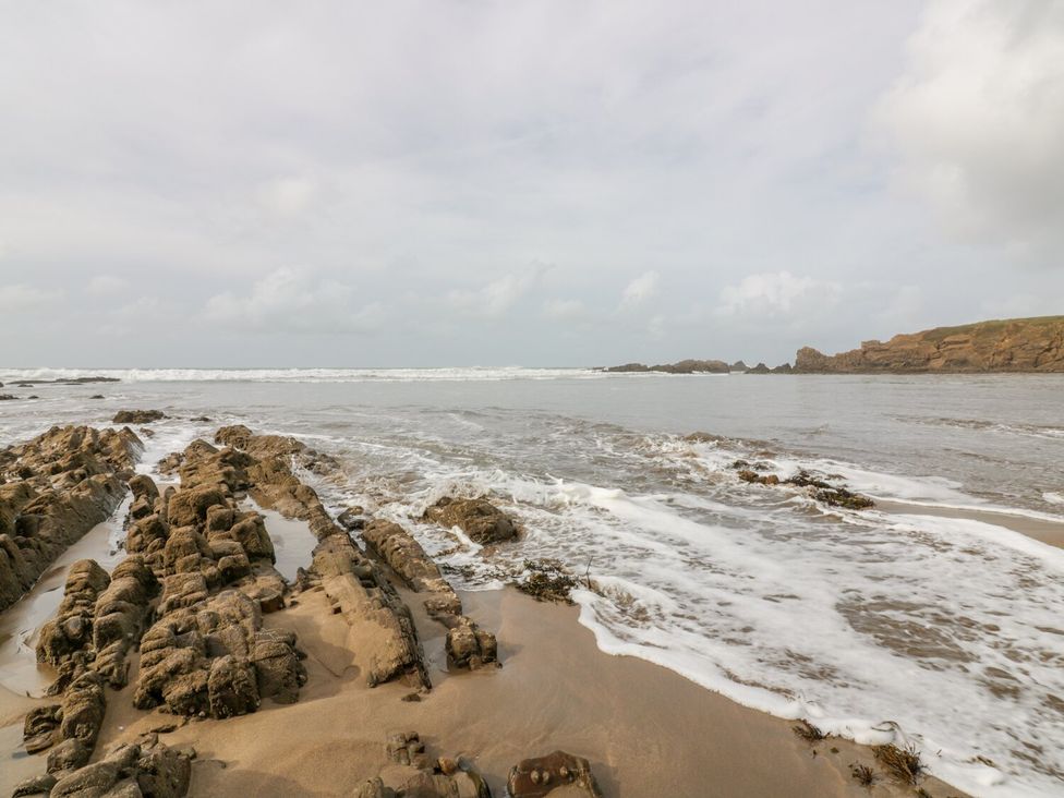 A beach with rock formations and waves at Parnacott in Holsworthy