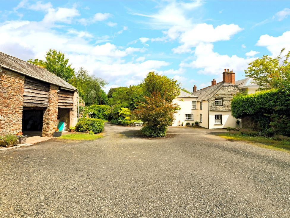 An outdoor view of a house and barn with trees at Parnacott in Holsworthy