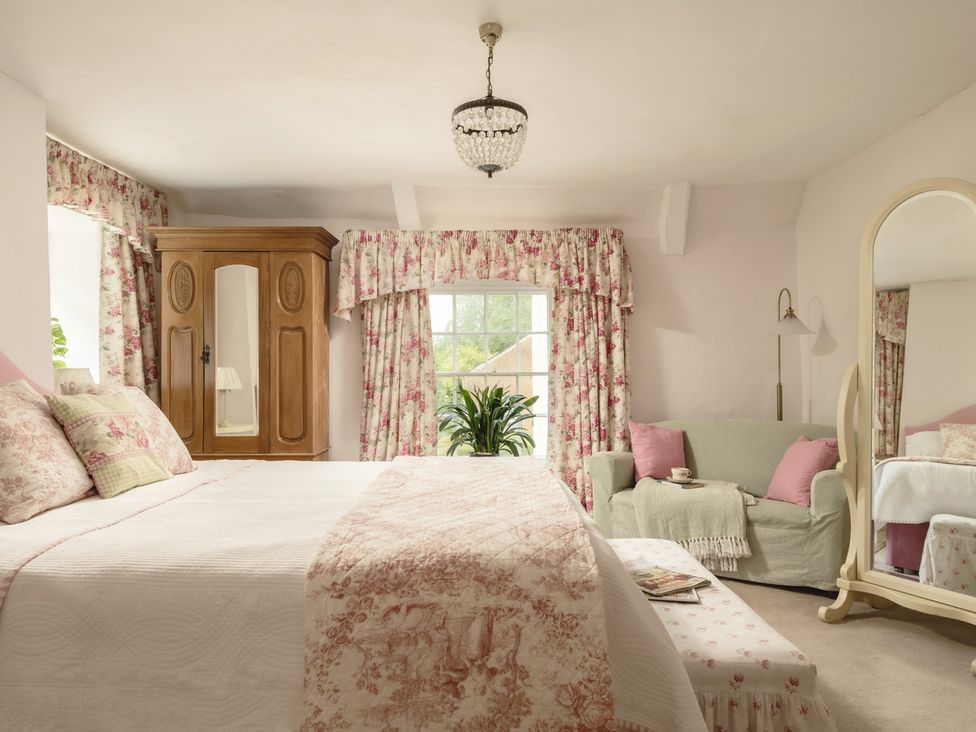 A bedroom with a bed and armchair at Parnacott in Holsworthy