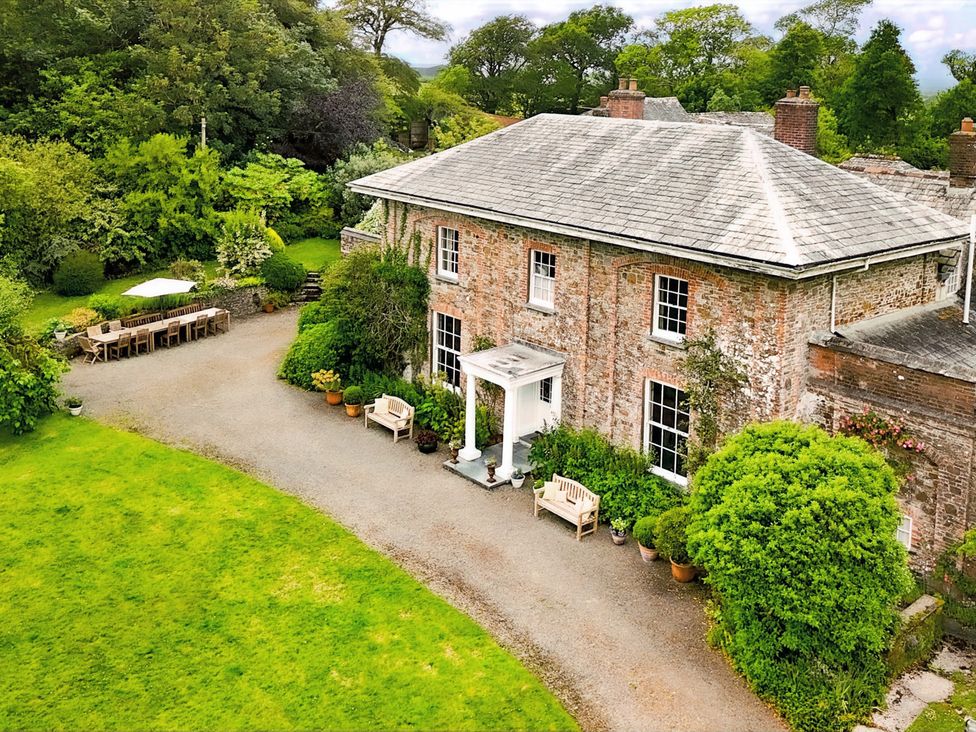 An outdoor view of a house with a garden and seating area at Parnacott in Holsworthy