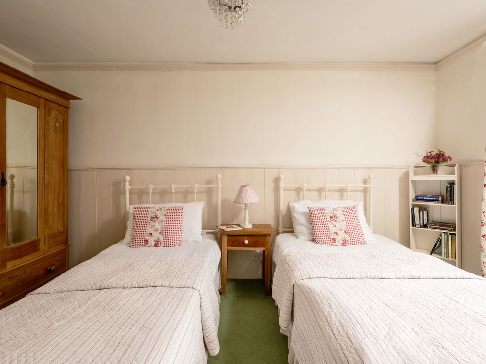 A bedroom with two beds and a wardrobe at Parnacott in Holsworthy