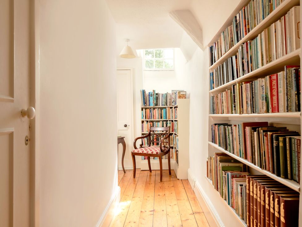 A hallway with a bookshelf and a chair at Parnacott in Holsworthy