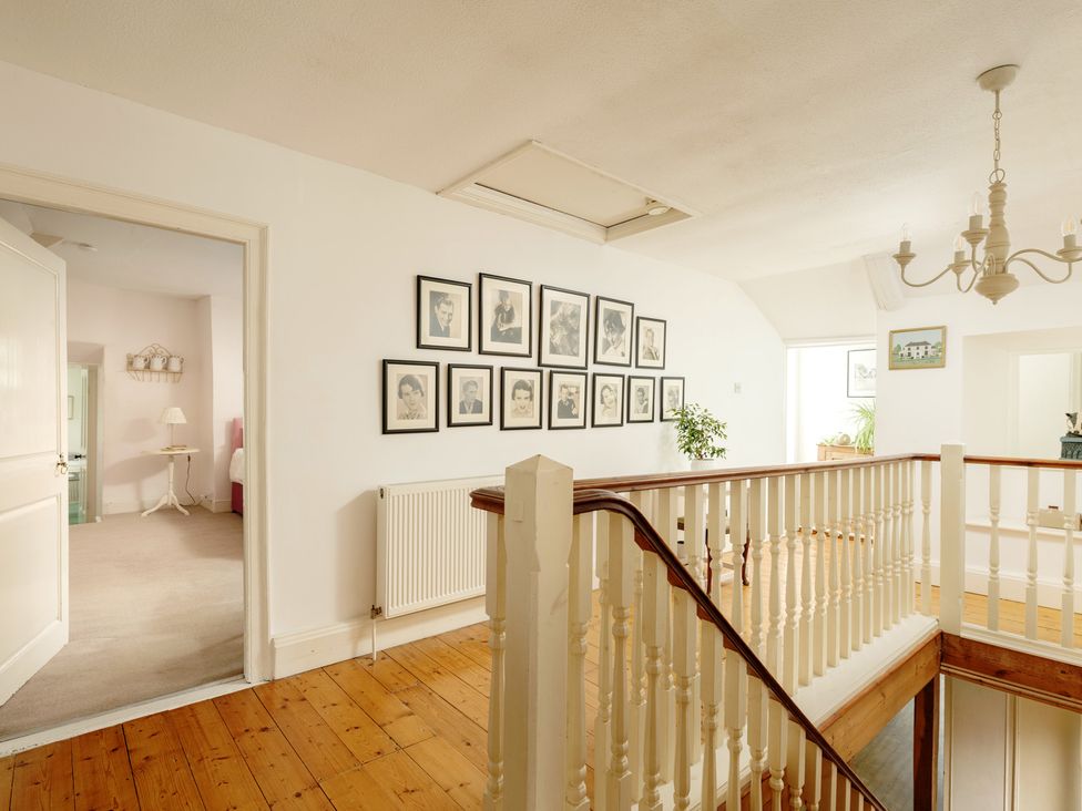 A landing with framed pictures and a staircase at Parnacott in Holsworthy