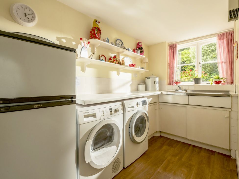 A laundry room with appliances and shelves at Parnacott in Holsworthy