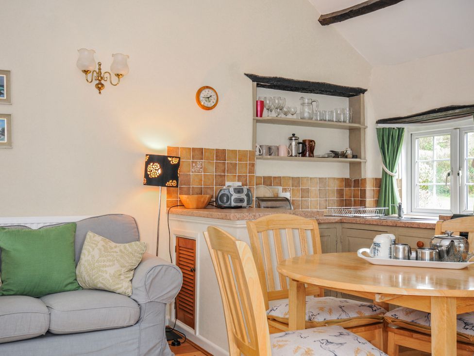 A kitchen with a dining table and sofa at Tumrose Cottage in Blisland