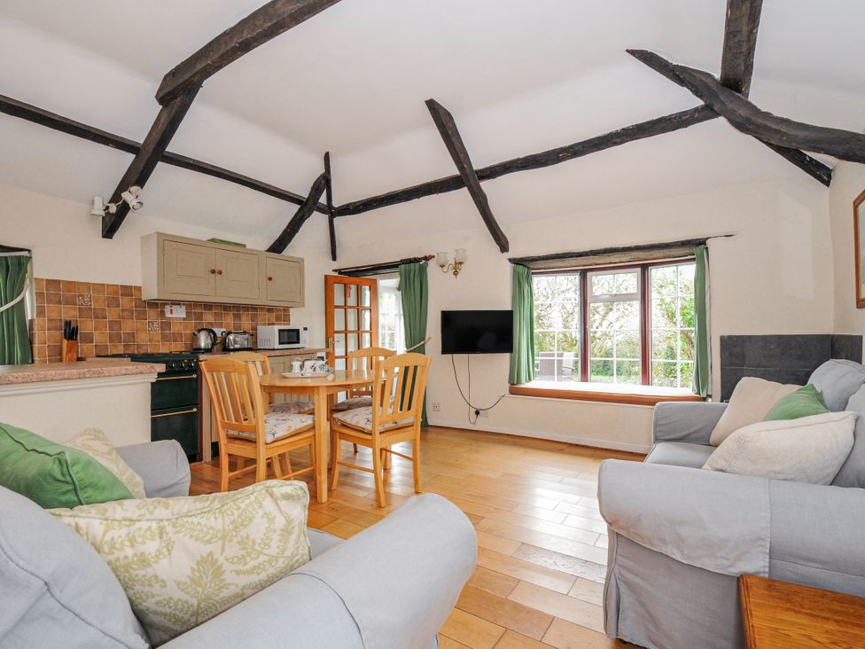 A living room with a dining table and kitchen unit at Tumrose Cottage in Blisland
