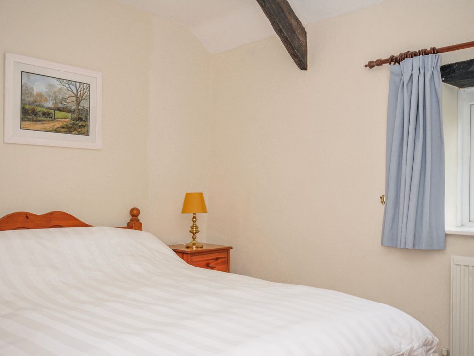 A bedroom with a bed and lamp at Tumrose Cottage in Blisland