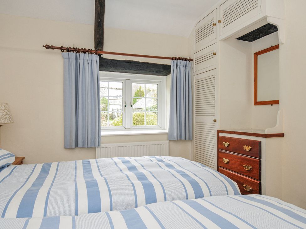 A bedroom with two beds and a window at Tumrose Cottage in Blisland