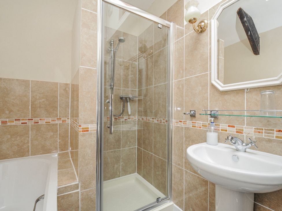 A bathroom with a shower, bathtub, and sink at Tumrose Cottage in Blisland