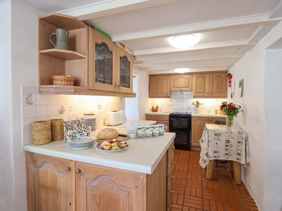 A kitchen with wooden cabinets and a table setting at Agar Cottage in Trelights, near Port Isaac