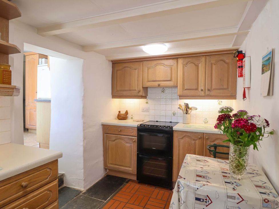 A kitchen with cabinets and a table at Agar Cottage in Trelights, near Port Isaac